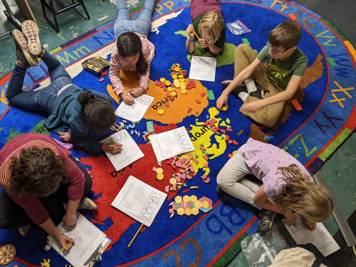 Children collaborating on a colorful math activity at a workshop table