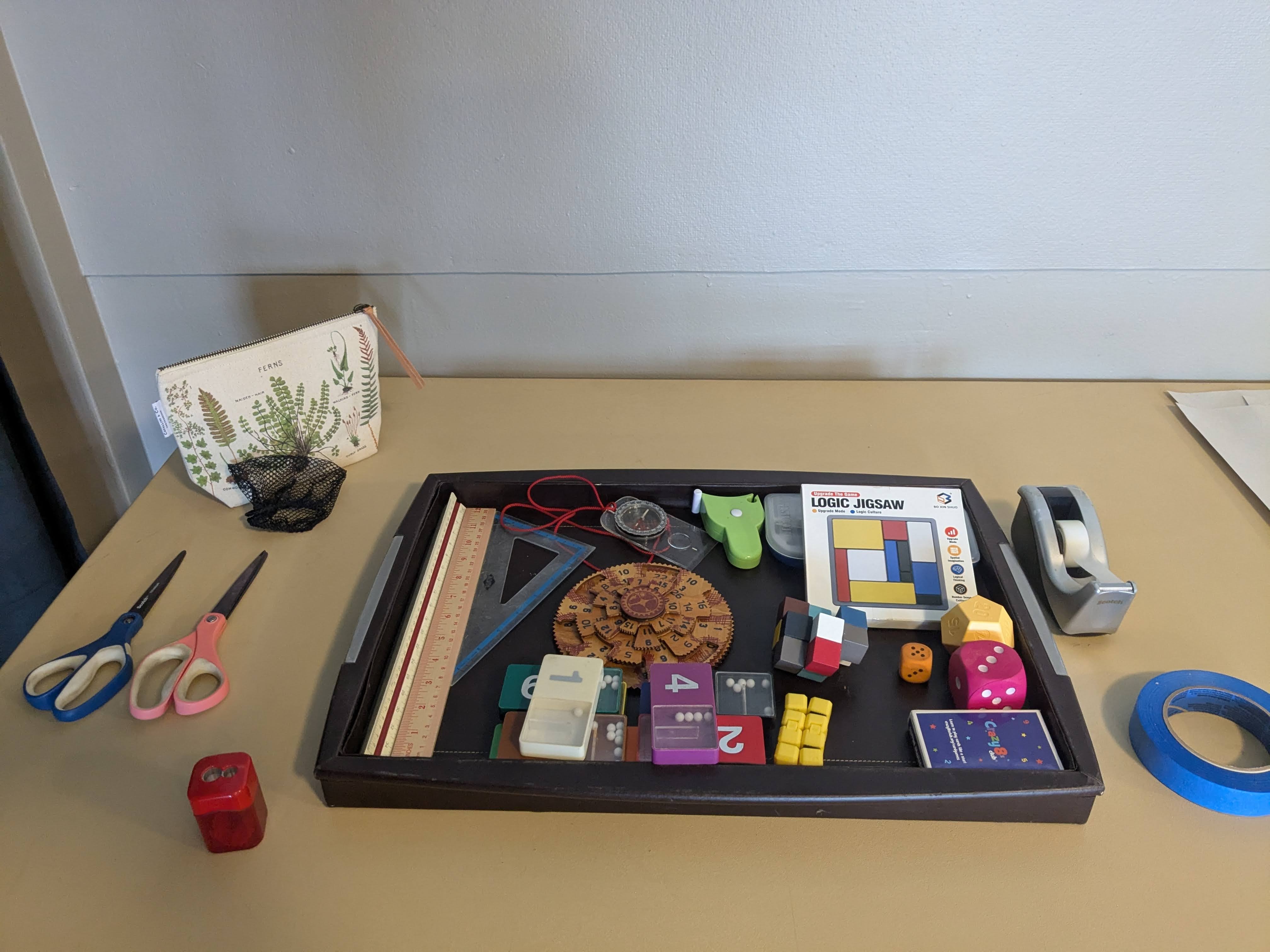 A tray of colorful math manipulatives, dice, puzzles, and tools for hands-on learning